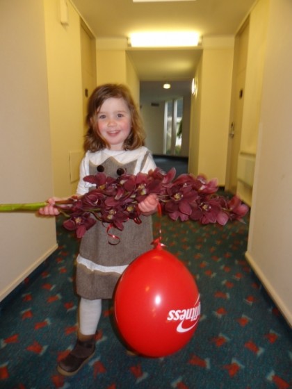 Paula’s gorgeous little daughter Rose carrying our precious orchids and a City Fitness balloon